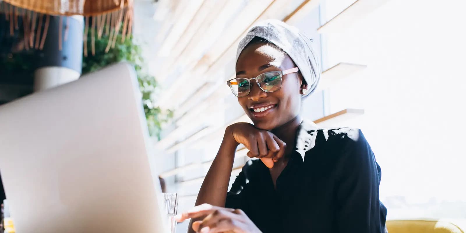 Freelancer smiling at a laptop in a sunlit café