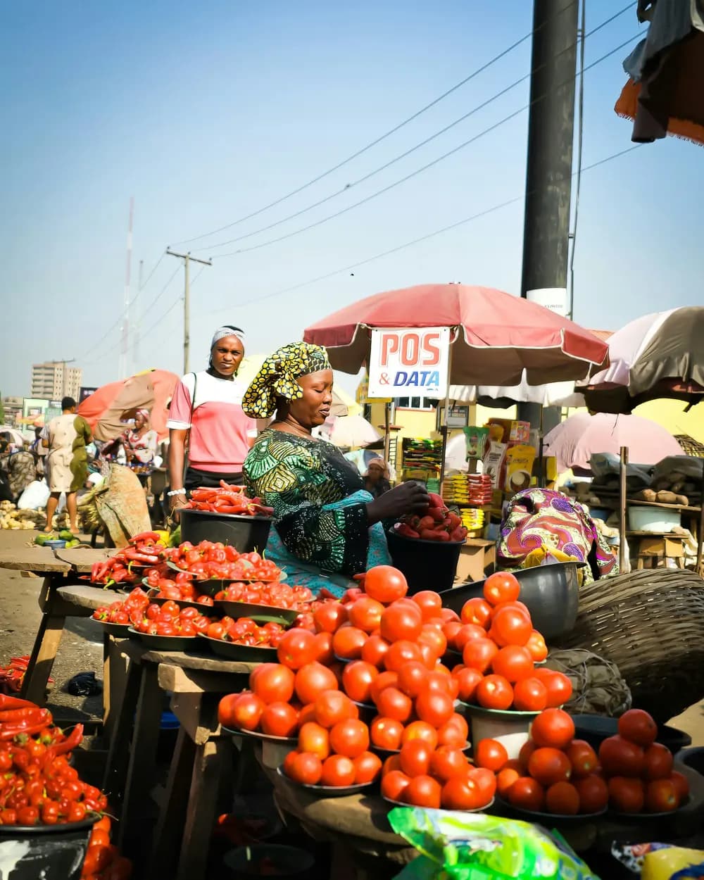 Trader at a roadside market stall piled with tomatoes and peppers