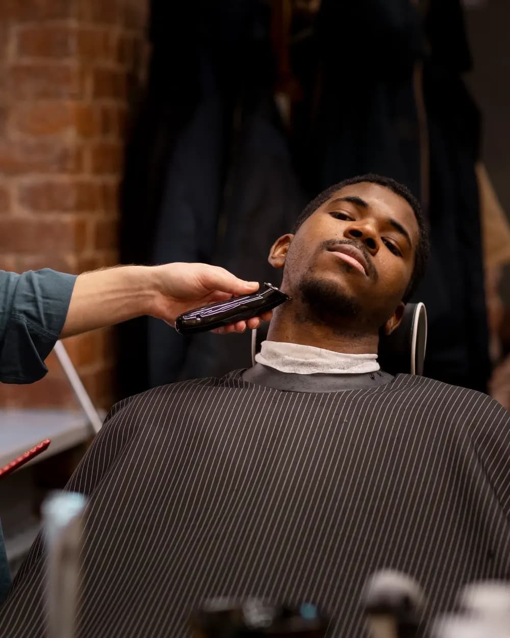 Barber trimming a customer's beard with clippers
